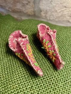 two small pink shoes sitting on top of a green cloth