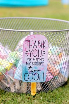 a metal basket filled with lots of toys on top of a grass covered field next to a sign that says thank you for making my birthday cool