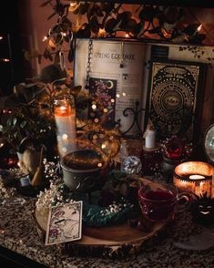 a table topped with candles and other items on top of a wooden tray next to an open book