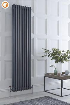 a white radiator in the corner of a room next to a table and potted plant