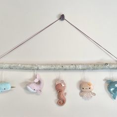 five stuffed animals hanging from a clothesline on a white wall in a nursery or kids's room