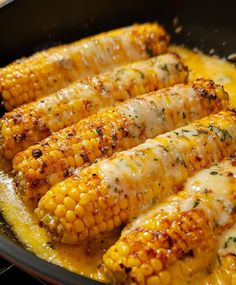 grilled corn on the cob in a skillet with melted cheese and herbs