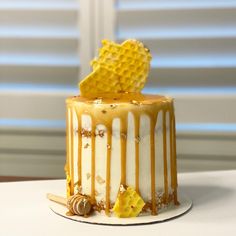 a yellow and white cake with honey drizzles on it's top