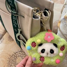 a hand holding a small keychain with a panda face on it's front