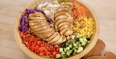 a large wooden bowl filled with different types of vegetables and meat on top of it