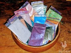 a wooden bowl filled with lots of different colored foil bags on top of a table