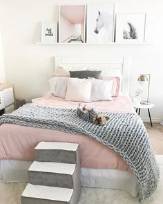 a white and pink bedroom with pictures on the wall above the bed, stairs leading up to it