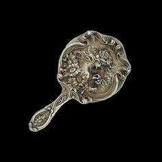 a silver spoon with an ornate design on it's face and head in the middle