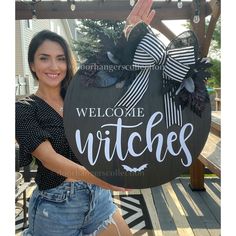 a woman holding up a welcome witches sign