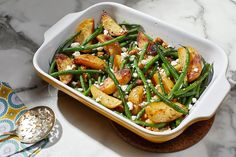 a white dish filled with green beans and potatoes