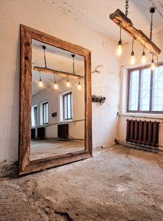 an empty room with a large mirror on the wall and lights hanging from the ceiling