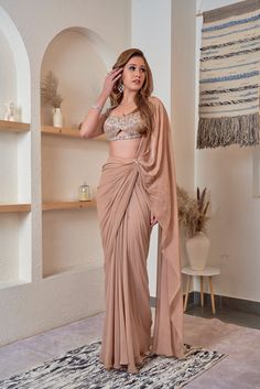 This whimsical nude shade saree is crafted with premium georgette. Paired with a gorgeous bralette and tasseled sleeves, embellished with nalki, moti, and stones this drape is a charismatic choice for your intimate soiree. Delivery Period: 2-3 weeks Draping Dress, Baju Kahwin, Saree Wearing Styles, Draped Saree, Fashionable Saree Blouse Designs, Fancy Sarees Party Wear, Indian Fashion Saree, Drape Saree, Saree Designs Party Wear