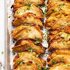 baked tortillas on a baking sheet lined with parchment paper and garnished with fresh parsley