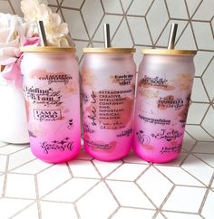 three pink soda cans sitting next to each other on a tiled floor with flowers in the background