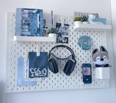 a white wall mounted shelf with headphones, books and other items on top of it