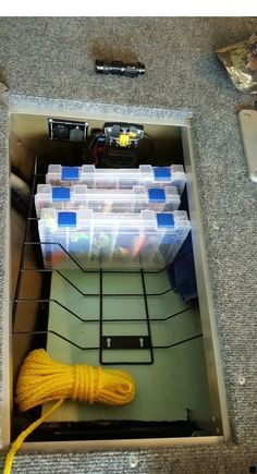 there is a yellow rope in the bottom of an open box with plastic containers on it