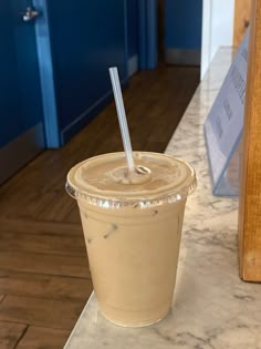 a drink in a plastic cup with a straw on the top sitting on a counter