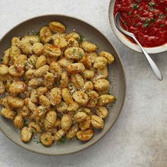 a bowl of food next to a plate with sauce