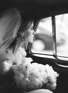 a black and white photo of a woman sitting in a car with her head out the window