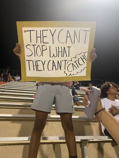 a man holding a sign that says they can't stop what they can't catch