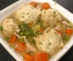 a white bowl filled with chicken and dumplings on top of a black countertop