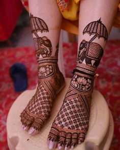 the legs and feet of a woman with henna tattoos on their feet, sitting on top of a stool