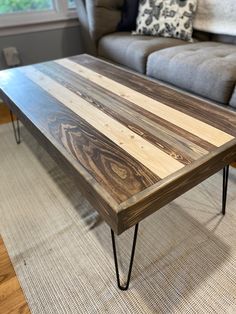 a wooden table sitting on top of a carpeted floor next to a gray couch