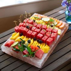 a platter filled with watermelon, oranges and other fruits on ice