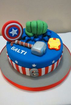 a birthday cake with captain america decorations on it's top and an iron man helmet