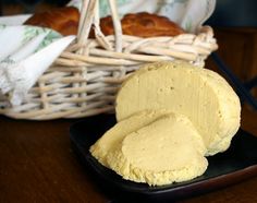 two pieces of bread on a black plate next to a basket with croissants in it