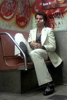 a man sitting on top of a metal bench in front of a wall with graffiti