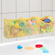 three bins filled with toys sitting on top of a bathtub next to a white tiled wall