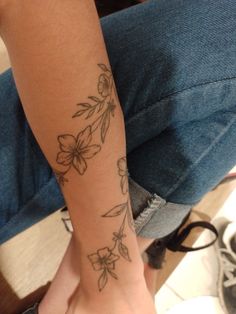 a woman's arm with flowers on it and a tattoo design on the wrist