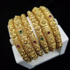 "* Handcrafted Gold Plated 6 Bangle Set. Sold as a set. * Bangles with pretty semi-precious Ruby and emeralds stones * High Quality 22 K Gold Plated- 6 Bangle set 2.4 ( 2.25\" diameter of the inner circle) ; 2.6 ( 2.40\" diameter of the inner circle); 2.8 (2.47\" diameter of the inner circle) Gorgeous gold-plated bangle/ bracelet best exemplifies the careful craftsmanship done on it -- a specialty at Nemali Jewelry. It has a special tone of elegance attached to it. The intricate handmade design 6 Bangles Set Gold, Luxury Handmade Bangle For Festive Occasions, Green Jewelry For Marriage And Festivals, Traditional Bangle For Anniversary, Traditional Heavy Bangle For Anniversary, Traditional Anniversary Bangle, Gold Heavy Bangle For Anniversary, Traditional Gold Bridal Sets For Anniversary, Green Wedding Bangle With Intricate Design