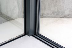 the corner of a room with a glass door and concrete wall in the back ground