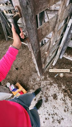 a person holding a cell phone up to the side of a wooden structure with writing on it