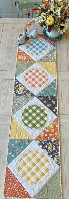 a table runner made with patchwork quilts and flowers on top of the table