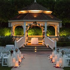 the gazebo is decorated with flowers and candles for an outdoor wedding ceremony at night