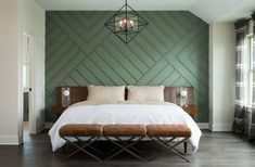 a bedroom with green walls and white bedding, wooden bench in the foreground