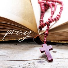 an open book with a wooden cross on it and the words pray written in white