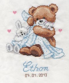 a cross - stitch baby's birth card with a teddy bear holding a kitten