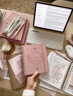 a person is holding a notebook in front of a laptop and several other items on a desk