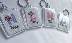 four cross stitch keychains with different designs on them