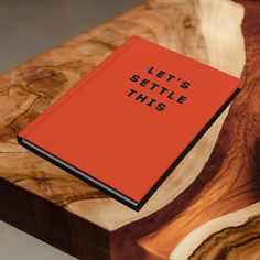 an orange book that says let's seattle this sitting on top of a wooden table