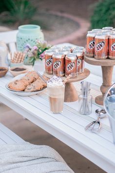 an outdoor table with food and drinks on it, including cookies and milkshakes