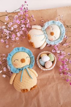 three crocheted stuffed animals sitting next to each other in front of pink flowers