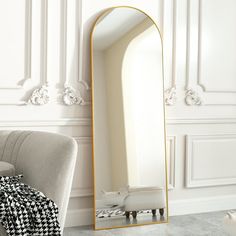 a mirror sitting on top of a white wall next to a chair