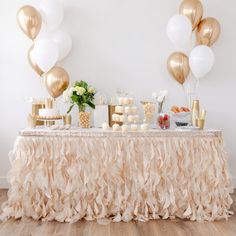 a table topped with lots of desserts and balloons on top of a wooden floor