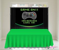 a green table cloth with a video game on sign in the middle and an image of a controller behind it