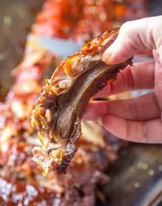 a person holding up a piece of meat with sauce on it